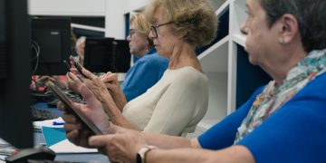 Un grupo de personas mayores siguiendo las instrucciones de una docente en sus teléfonos móviles. Foto: Fundación La Caixa