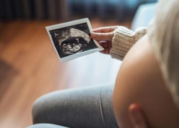 Mujer embarazada que mira su informe de ultrasonido.© Shutterstock / oatawa